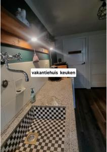 a bathroom with a sink and a checkered floor at 1x Luxe trekkershut of 1x vrijstaand vakantiehuisje Peperkamp in Zelhem