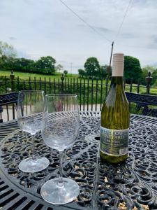 a bottle of wine sitting on a table with two glasses at St Milburga Chapel in Stoke Saint Milborough