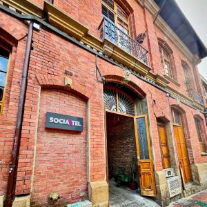 a red brick building with a sign on it at Socialtel Candelaria Bogotá in Bogotá