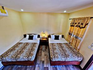 a room with two beds and a table with a lamp at Hostal Juarez Ataco in Concepción de Ataco