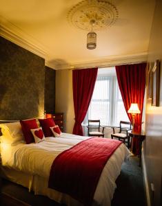 a bedroom with a large bed with red curtains at Coalminer's Cottage in Gateshead