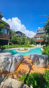 トゥルムにあるRide & Relax at Humana Tulum 2BR Free Bikes Near Beachの庭園内のスイミングプール(ソファ2台付)