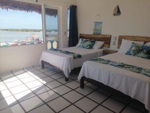 two beds in a room with a view of the ocean at Hotel y Restaurante Macumba in Río Lagartos
