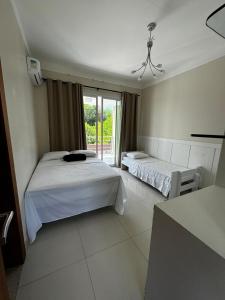 a bedroom with two beds and a window at Casa Fênix in Porto Seguro