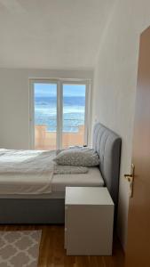 een slaapkamer met een bed met uitzicht op de oceaan bij Panorama Apartment Marija in Stanići