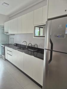 a kitchen with white cabinets and a stainless steel refrigerator at Mar de ensueños in Florianópolis