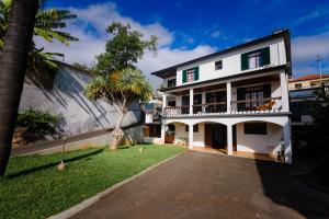 uma casa branca com uma palmeira e uma entrada em Villa Ocean Bay Funchal By Empório no Funchal