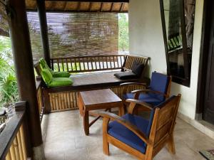 a porch with two chairs and a table and a bench at Jukung Bali Bungalow in Amed