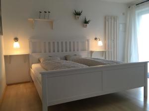 - une chambre avec un grand lit blanc éclairé dans l'établissement Innsbruck Apartment Nigler, à Innsbruck