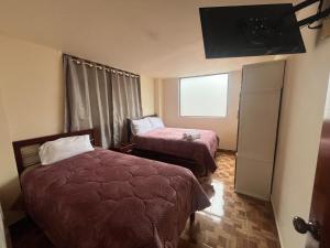 a hotel room with two beds and a television at Apartamento recien estrenado in Baños