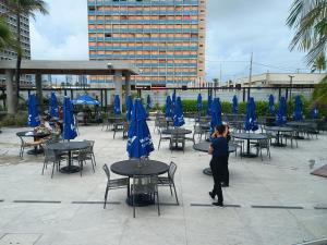 a woman standing in front of tables with blue umbrellas at Salinas Premium Resort in Salinópolis +7 photos