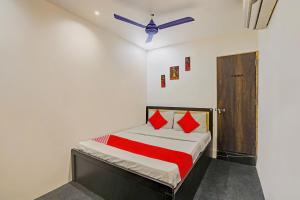 a bedroom with a bed with red pillows and a ceiling fan at Hotel O Lotus Hotel in Surat