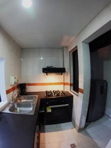 Una pequeña cocina con fregadero y estufa. en Casa cerca de concierto Marc Anthony Med Plus, en Bogotá