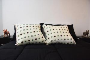 Una cama con tres almohadas de lunares. en Casa cerca de concierto Marc Anthony Med Plus, en Bogotá