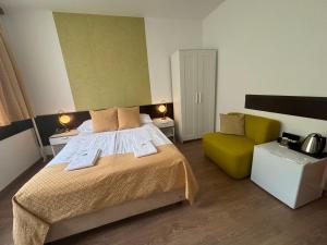 a bedroom with a bed and a yellow chair at Hotel Gloria Budapest City Center in Budapest