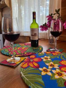 a bottle of wine and two glasses on a table at Cabana Vale Matutu in Aiuruoca +33 photos