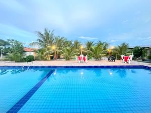 a large swimming pool with red chairs and tables at Pousada trilha da capivara in Coronel José Diaz