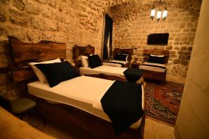 ein Schlafzimmer mit drei Betten in einem Zimmer mit einer Steinwand in der Unterkunft Sultan Konağı Hotel - Heritage Stay in Mardin
