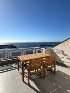 a wooden table and benches on a balcony overlooking the ocean at Ático Rocamar in La Restinga