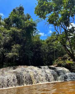 una cascata sul lato di un fiume alberato di Chalés Cachoeira do Cafundó a Bueno Brandão