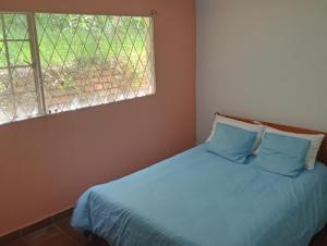 a bedroom with a bed with blue sheets and a window at La Juana Posada Campesina in Tenjo +8 photos