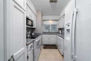 a kitchen with white cabinets and a sink at 550 Tarpon Pond Cottage in Seabrook Island +22 photos