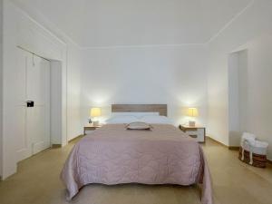 a white bedroom with a large bed and two lamps at L'Armonia - "La Capasa" in Noci