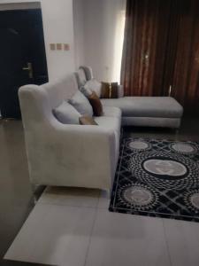 a white couch in a living room with a rug at Whitney white 1bedroom shortlet apartment 24hr light Stadium Road N55,000 in Port Harcourt