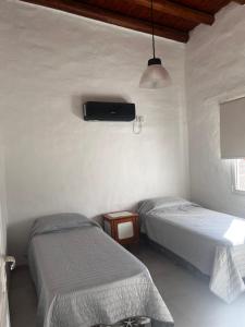 a room with two beds and a tv on the wall at SIESTA al Lago in El Nihuil