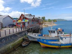 two boats are docked next to a dock at Calor y amor de hogar chilote in Castro