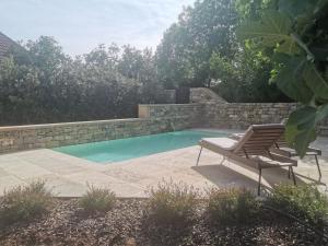a swimming pool with a bench and a chair next to it at La Maison Médiévale à colombage en Quercy in Puylagarde