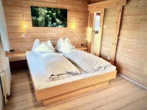 a bed in a wooden room with pillows on it at Rafting Camp Palfau in Palfau