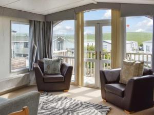 a living room with two chairs and a balcony at Skiddaw Lodges- The Lake District in Plumbland
