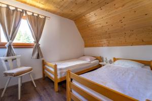 a bedroom with two beds and a chair and a window at Vikend Kuća Mirko in Risovac