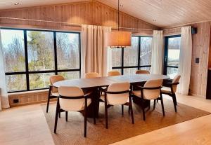 Un comedor con mesa y sillas y ventanas. en Immaculate Cabin in the Heart of Beitostølen, en Beitostølen