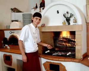 un hombre parado frente a un horno de ladrillo en Hotel Höllsteiner Hof en Steinen