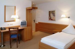 a hotel room with a bed and a desk with a television at Hotel Höllsteiner Hof in Steinen