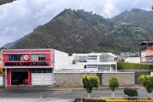 a red and white building with a mountain in the background at Apartamento recien estrenado in Baños