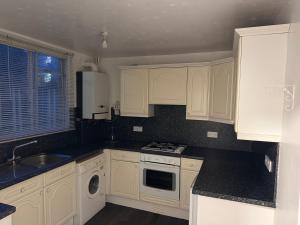 Una cocina blanca con gabinetes blancos y un fregadero. en Aso rock, en Dartford