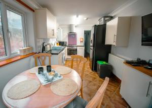 a kitchen with a wooden table and chairs in it at Purple Cloud Cosy 4 bed Cottage with Garden Parking Pet-Friendly in Portsmouth