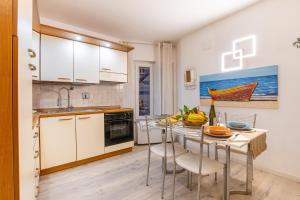 a kitchen with white cabinets and a table with chairs at Nel Borgo Antico in Riomaggiore