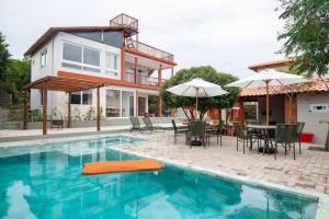 a house with a swimming pool with chairs and umbrellas at Bangalôs da chapad in Vale do Capao