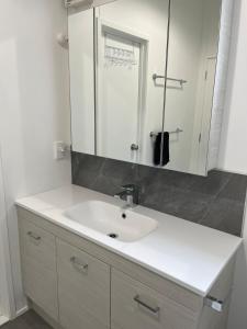 a bathroom with a white sink and a mirror at Starboard Retreat in Mahia