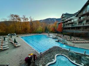 ein großer Swimmingpool in einem Resort mit Stühlen und Bäumen in der Unterkunft Ski In Ski Out Stowe Studio at Spruce Peak in Stowe