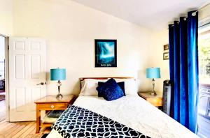a bedroom with a bed with blue curtains and two lamps at Kona Garden Retreat in Kailua-Kona
