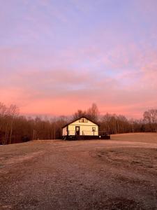 un fienile in un campo con un tramonto sullo sfondo di Stonebrook Hollow Cabin a Tidwell