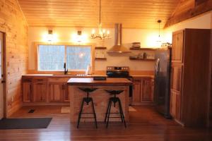 una cucina con armadi in legno e un'isola con sgabelli da bar di Stonebrook Hollow Cabin a Tidwell Altre 6 foto