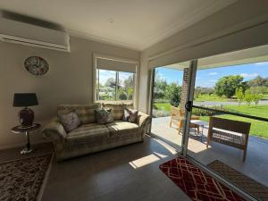 un soggiorno con divano e ampie finestre di Camellia Cottage Pet Friendly Farm Stay a Picton
