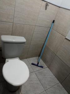 a white toilet in a bathroom with a mop at casarao24horas in Cuiabá