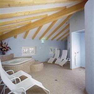 Zimmer mit Stühlen und einer Badewanne in einem Zimmer mit Holzdecken in der Unterkunft Hotel Olivo in Arco